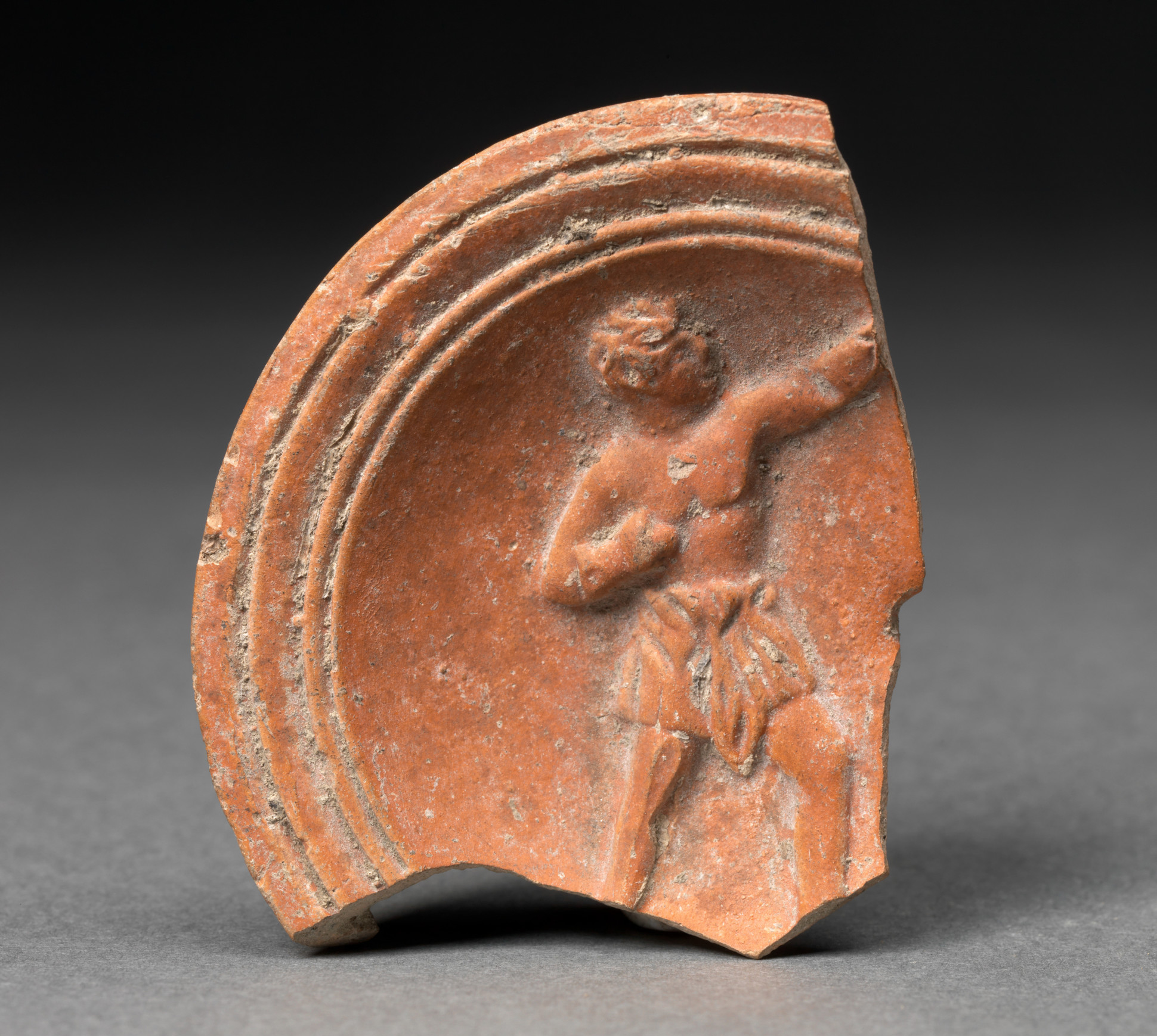 Unknown (Roman), Fragment from an oil lamp with boxer motif, 40-100 CE. Terracotta, 2 1/4 x 1 15/16 x 3/8 in. Gift of Charles Caryl Coleman. (28.8.7)